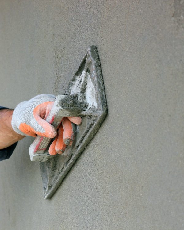 Man's hand plastering a wall with trowel. Selective focus.